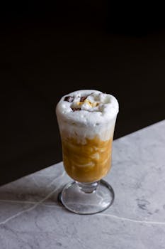 A delicious iced coffee topped with cream on a marble table, perfect for coffee lovers.