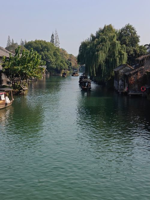 Free Peaceful canal view with traditional houses, lush greenery, and boats. Stock Photo