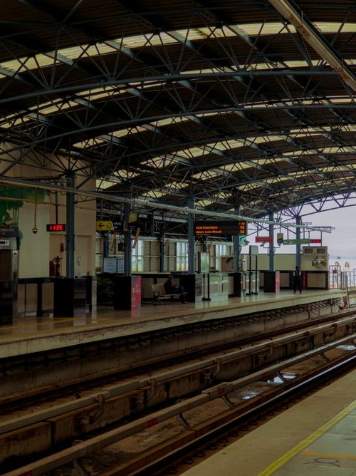 Free A spacious train station platform with steel structure roof and empty tracks, evoking a quiet, waiting atmosphere. Stock Photo
