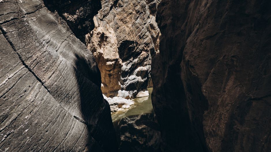 Hikers enjoying the clear turquoise pools and lush greenery of Wadi Shab, Oman