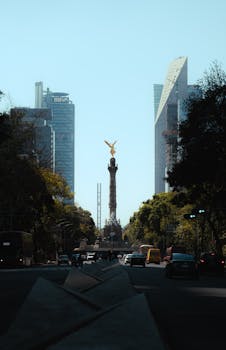 A view of the Angel of Independence monument in Mexico City with skyscrapers in the background.