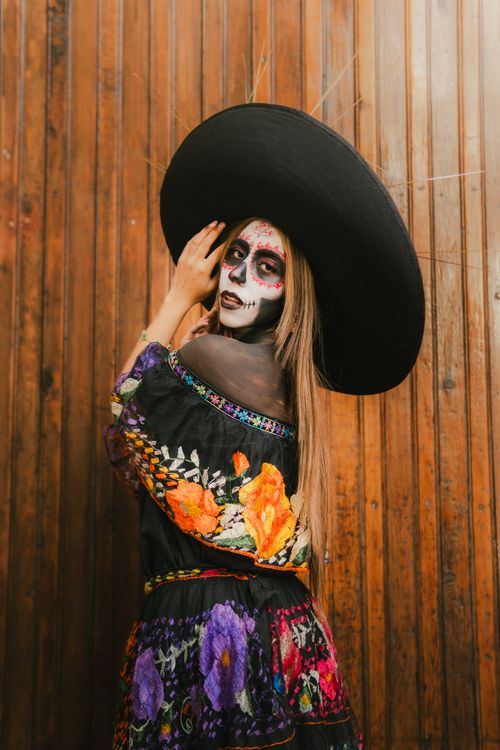 Free Portrait of a woman in Catrina makeup wearing a traditional Mexican dress for Day of the Dead celebration. Stock Photo