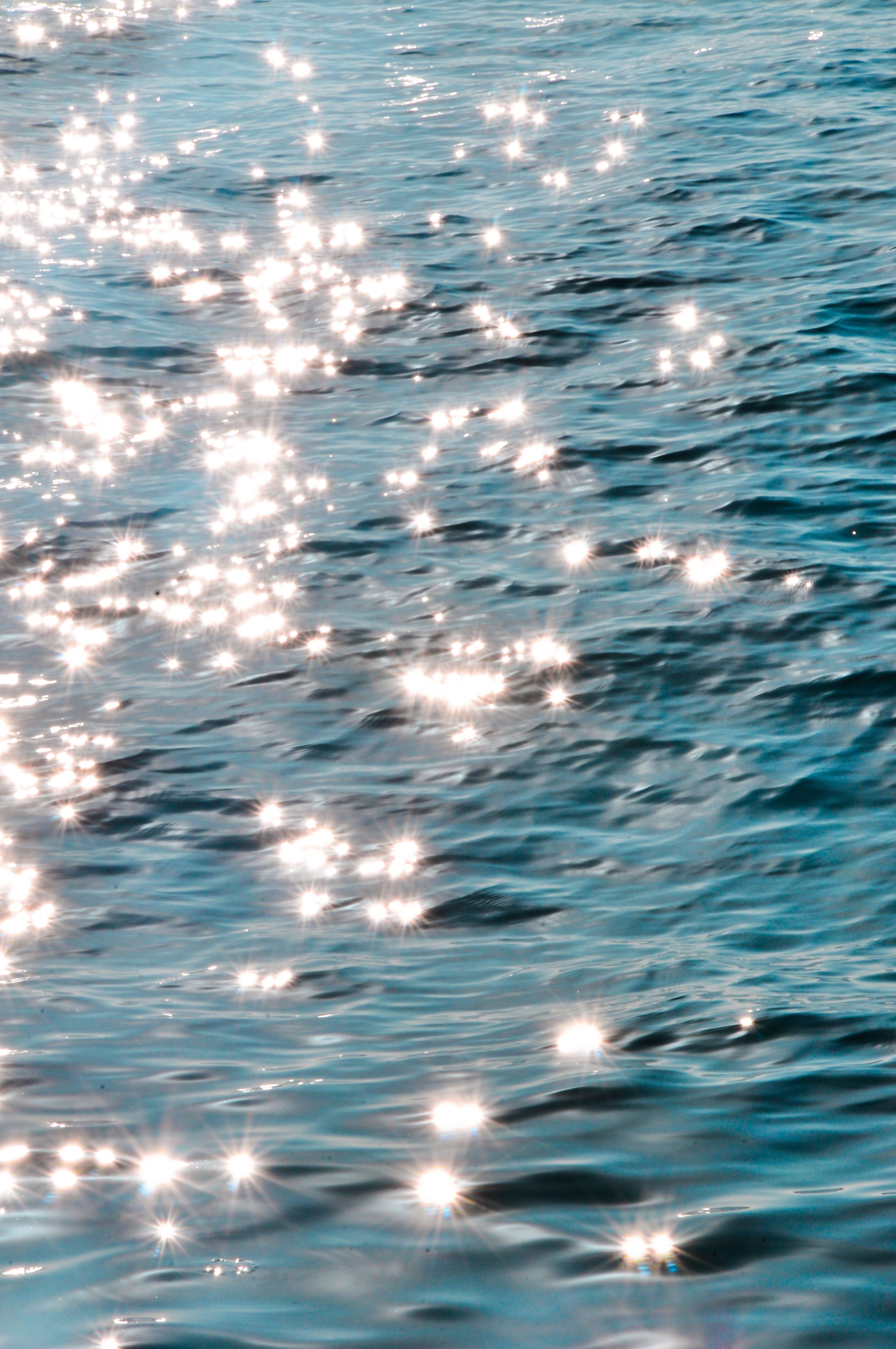 Vibrant sunlight sparkles on the ocean waves, creating a serene and mesmerizing effect.