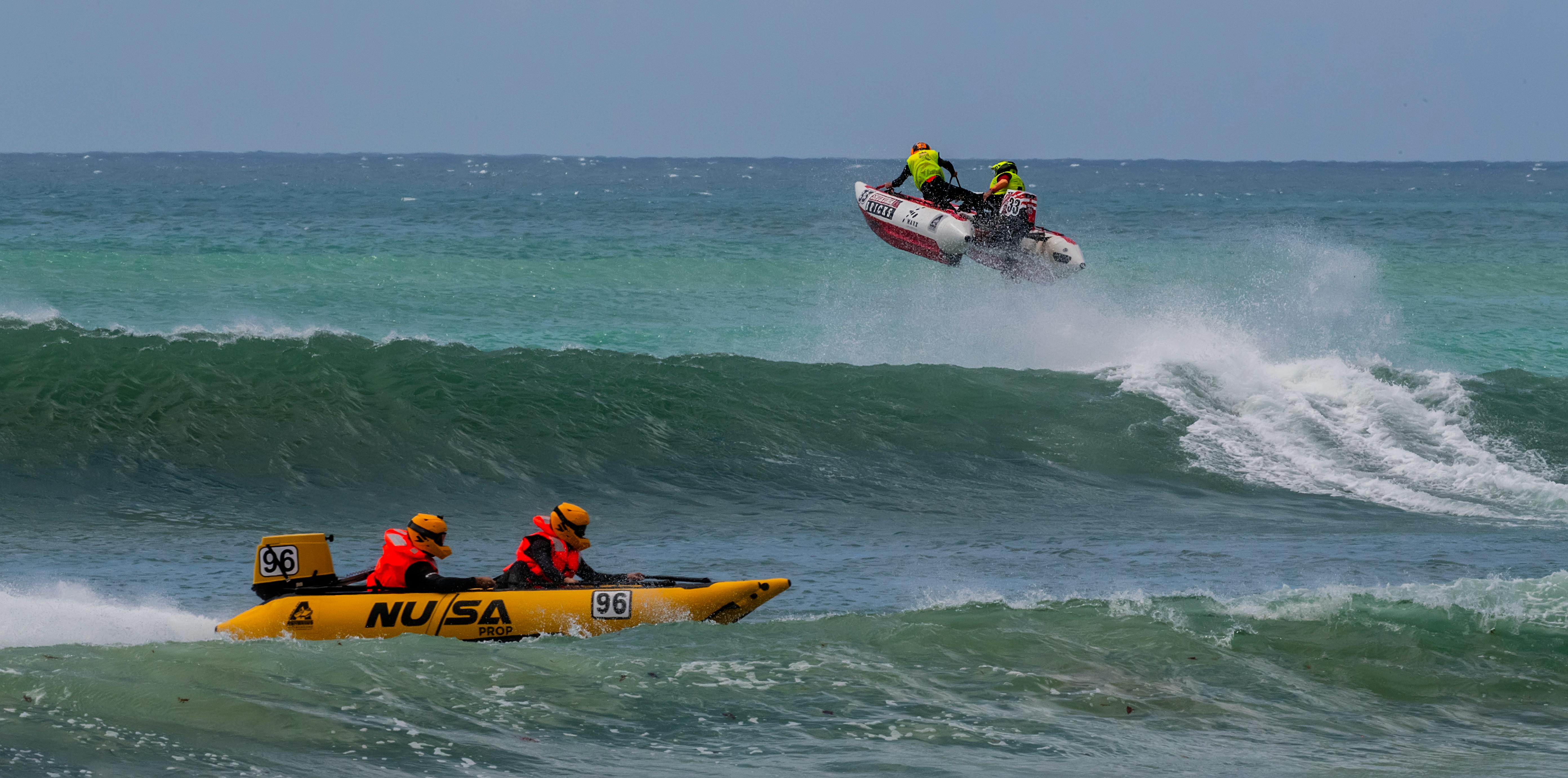 Exciting scene of jet boats racing over waves on the ocean, showcasing teamwork and adrenaline.