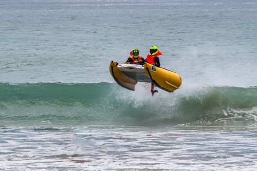 Free Two people in a motorized inflatable boat jumping over ocean waves, showcasing adventure and excitement. Stock Photo
