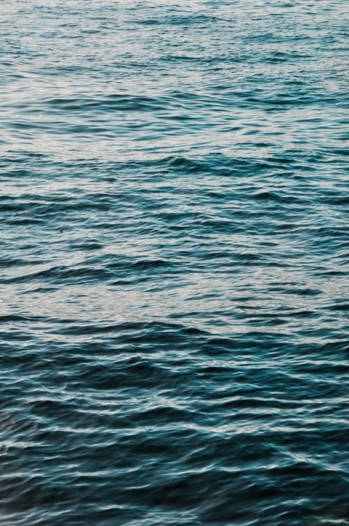 Free Tranquil view of ocean waves under a soft sunset light, capturing the peaceful sea surface. Stock Photo