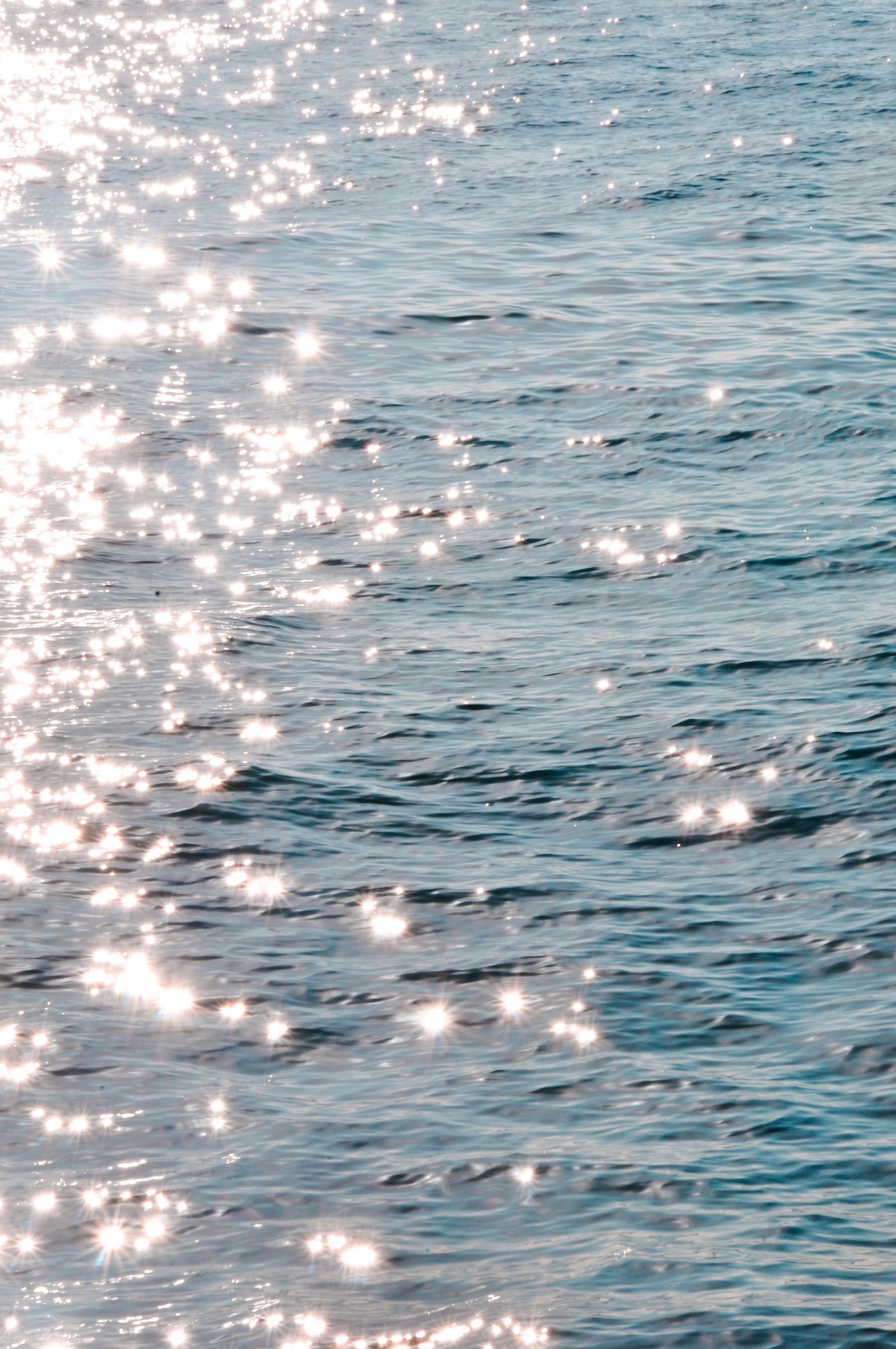 Sunlight sparkles brightly on ocean waves, creating a serene and calming effect.
