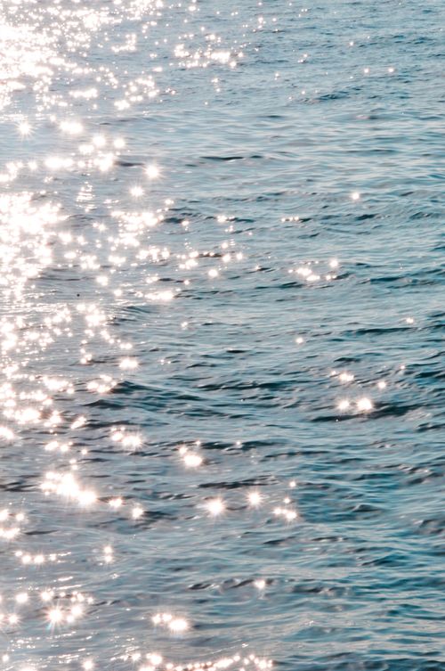 Free Sunlight sparkles brightly on ocean waves, creating a serene and calming effect. Stock Photo