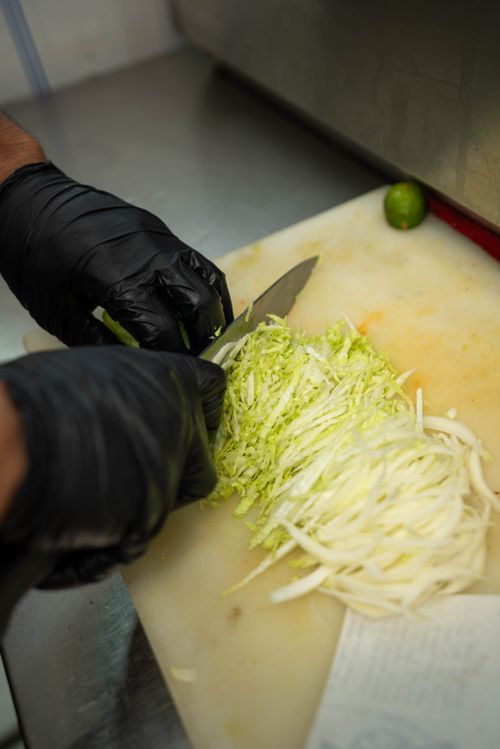 Free A chef expertly slicing fresh cabbage on a cutting board in a professional kitchen setting. Stock Photo