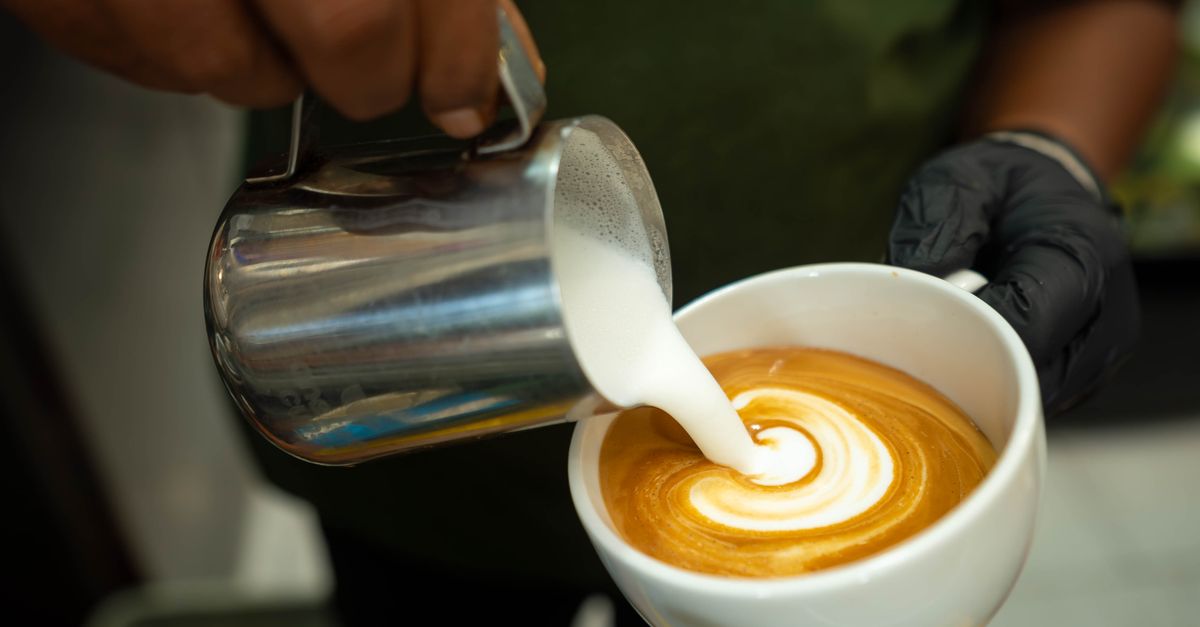 Close-up macro shot of milk swirling into hot espresso showing the vortex and crema formation