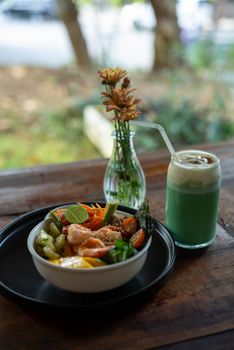 Delicious salad bowl with fresh vegetables and vibrant green juice on a rustic table outdoors.
