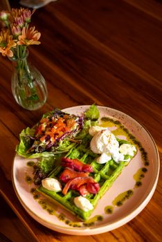 Delicious green waffles topped with creamy cheese, paired with fresh salad. Perfect for a gourmet breakfast.