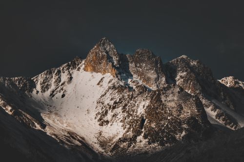 Free Breathtaking snow-covered mountain peaks under an ominous dark sky, captured in dramatic lighting. Stock Photo