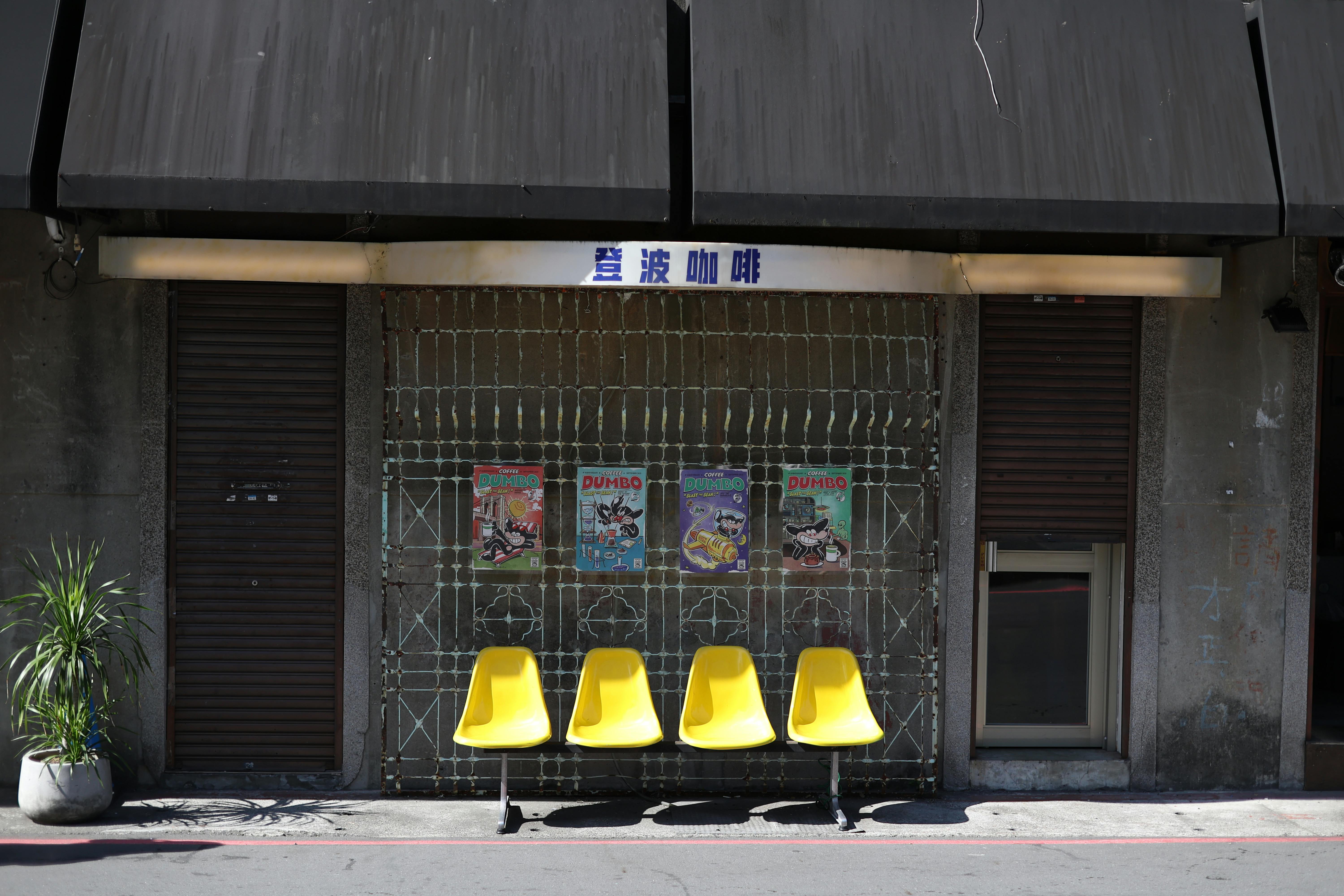 Zadarmo Rad žltých stoličiek oproti exteriéru kaviarne s farebnými plagátmi vytvára živú pouličnú scenériu. Fotka z fotobanky