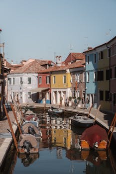 A serene canal scene with vibrant, colorful houses in Burano, Italy.