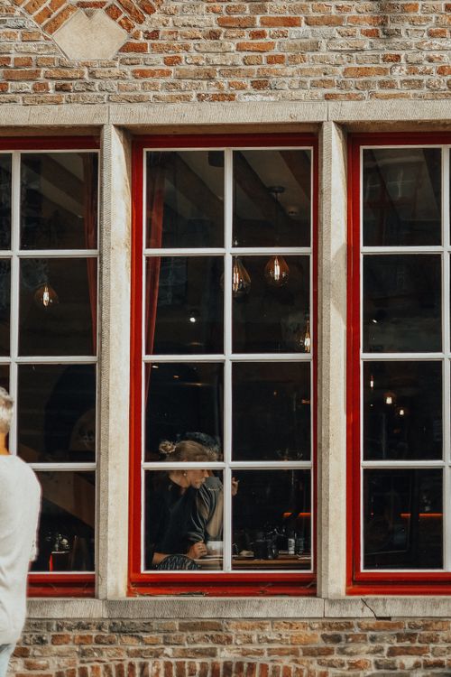 Free Warm interior of a cafe with people inside, seen through a large red-framed window. Stock Photo