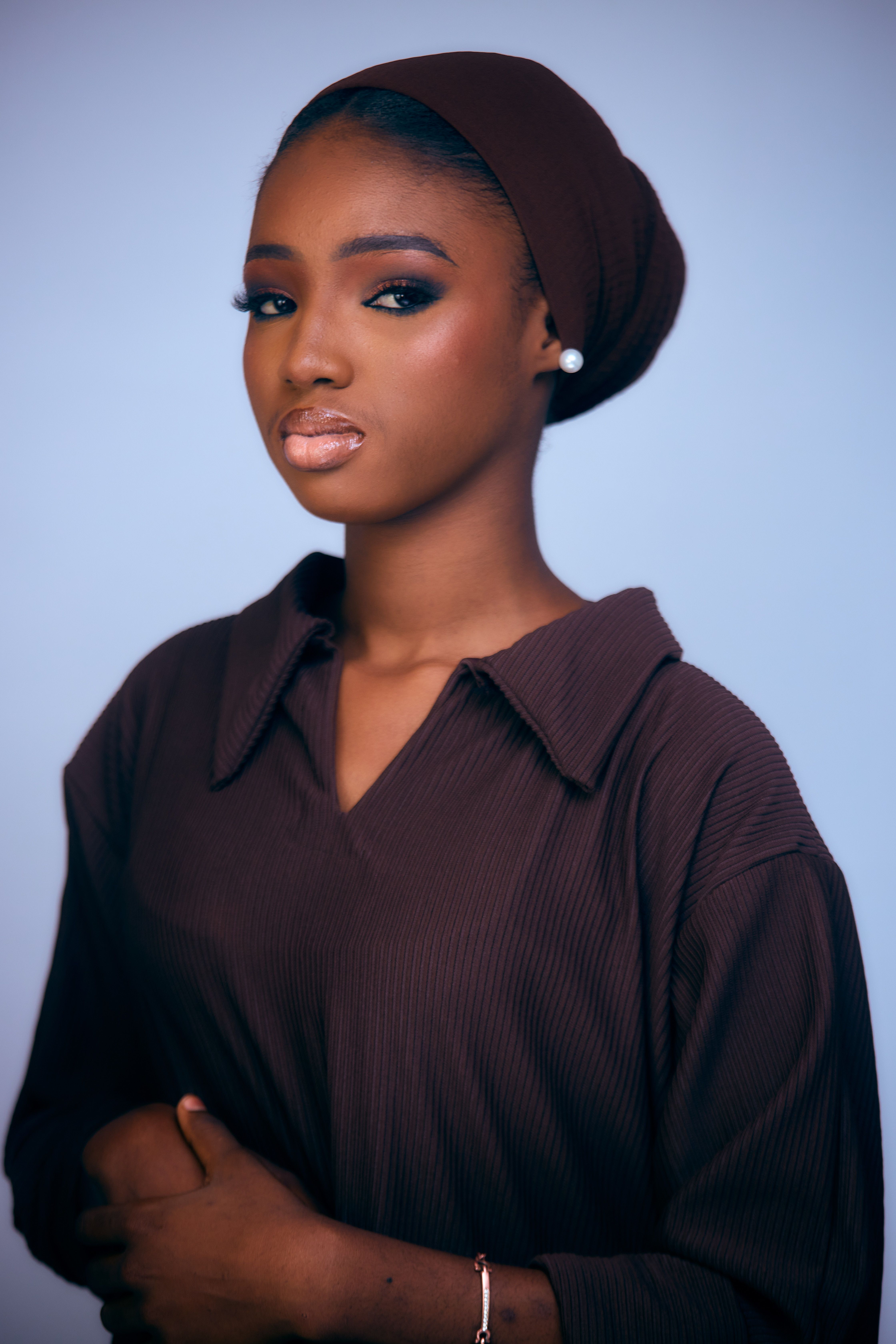 Stylish portrait of a woman wearing a brown outfit and headscarf, showcasing elegance and beauty.