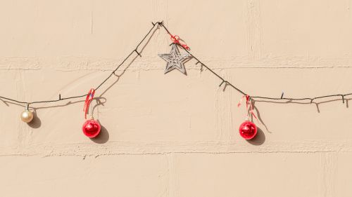 Free String lights and ornaments create a festive holiday atmosphere on a simple yellow wall. Stock Photo