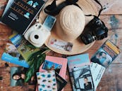 木桌上整齐地摆放着旅行配件，有草帽、相机和指南