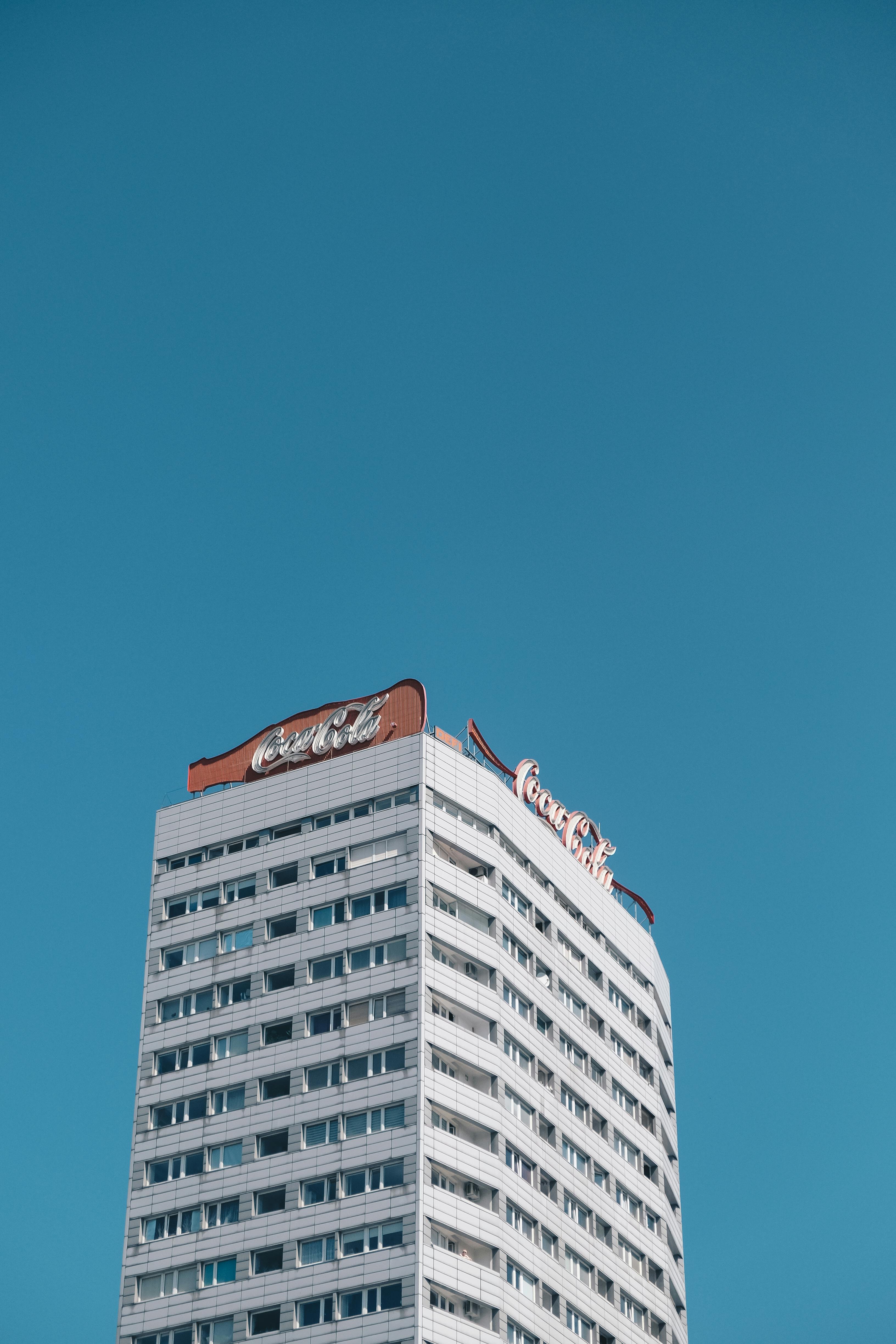 Free A high-rise building with iconic branding set against a vibrant blue sky. Stock Photo
