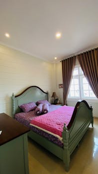 Charming bedroom featuring a vintage green bed and elegant decor, perfect for relaxation.