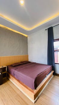 A stylish minimalist bedroom featuring a double bed and subtle lighting.