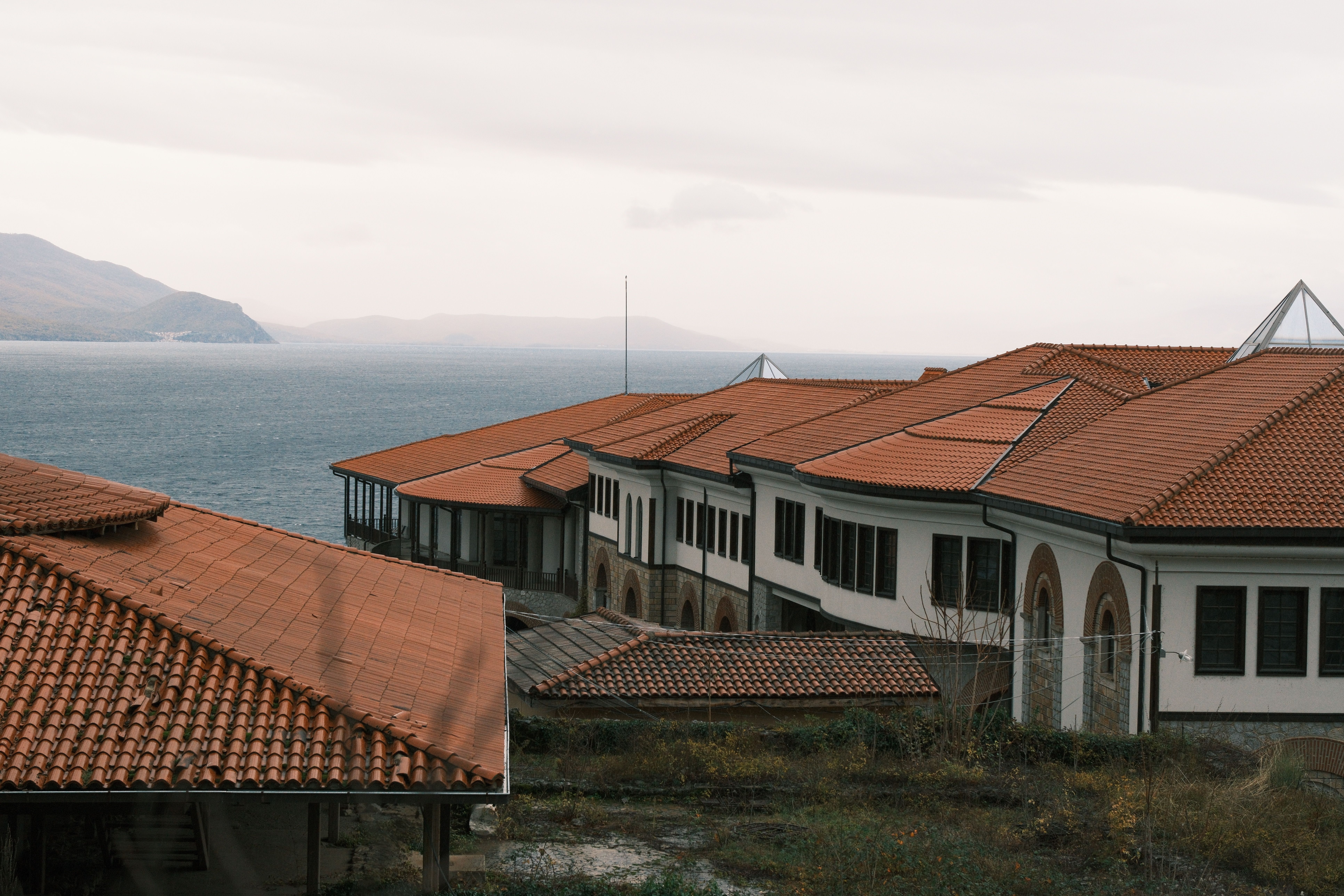Vue sereine de toits de tuiles rouges au bord d'une mer calme, évoquant le charme méditerranéen.