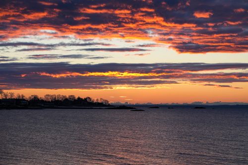 Free Vibrant sunset over a peaceful ocean with dramatic clouds and colorful sky. Stock Photo