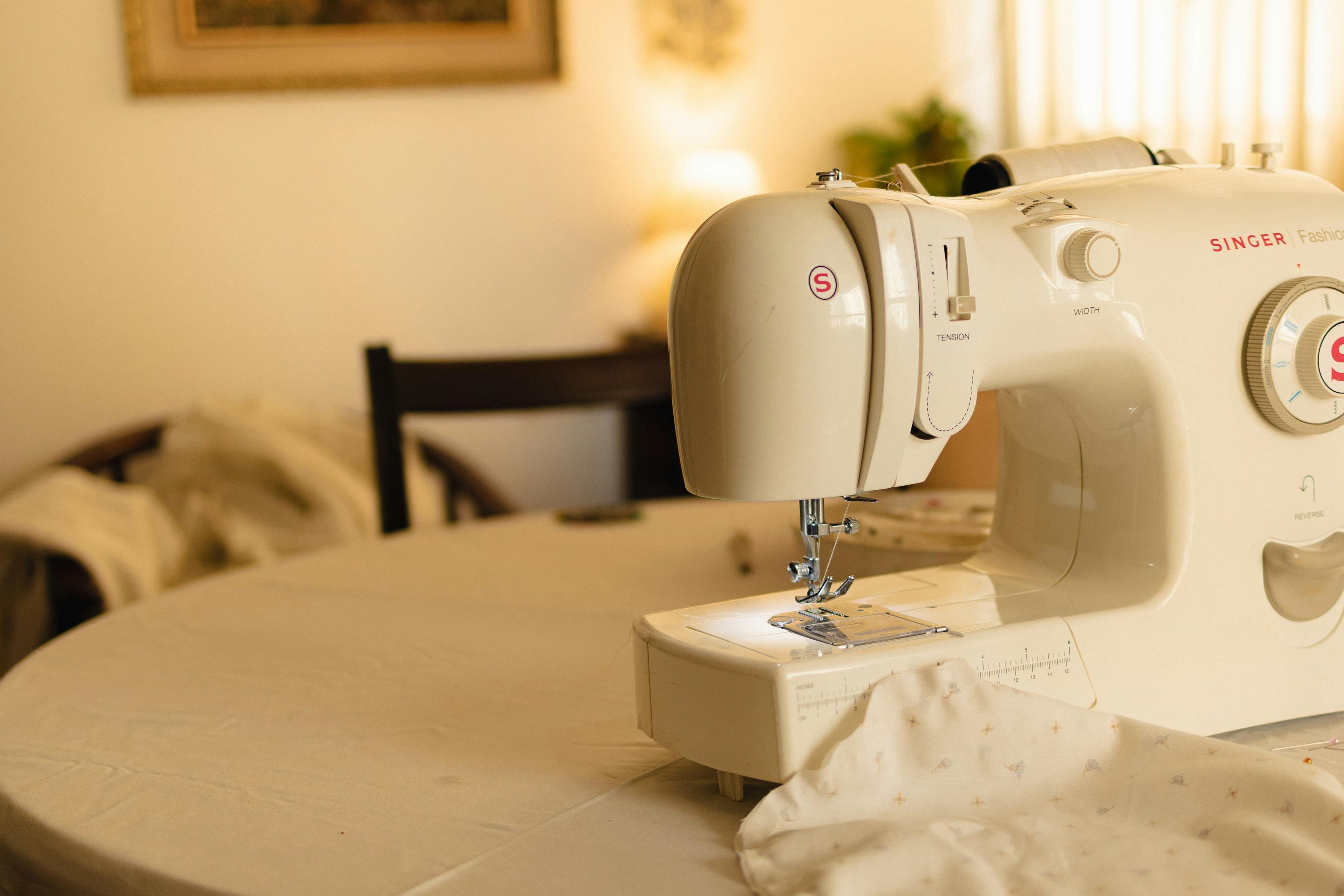 White sewing machine on a table in a cozy indoor setting, with soft lighting. — Maynard Longarm Quilting