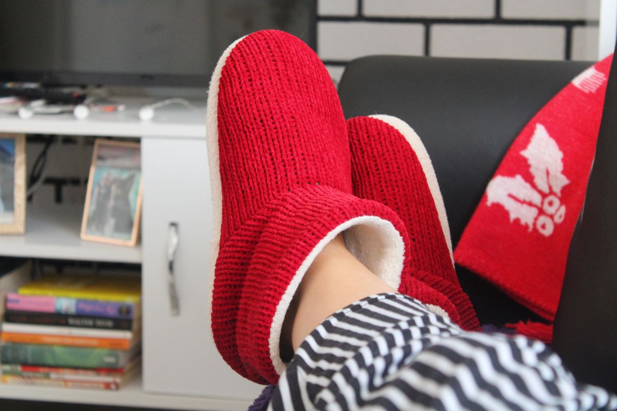 Cozy red slippers worn while relaxing indoors on a soft rug Cozy red slippers worn while relaxing indoors on a soft rug