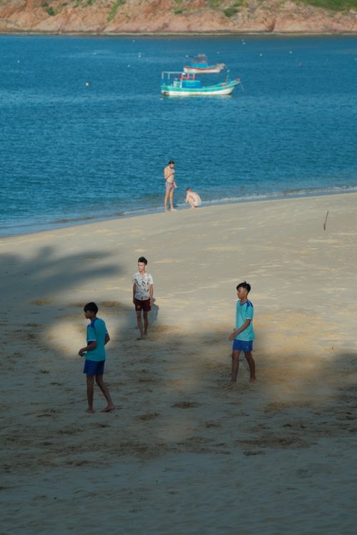 Free Group of children enjoying a sunny day at the beach, with a boat in the distant blue sea. Stock Photo