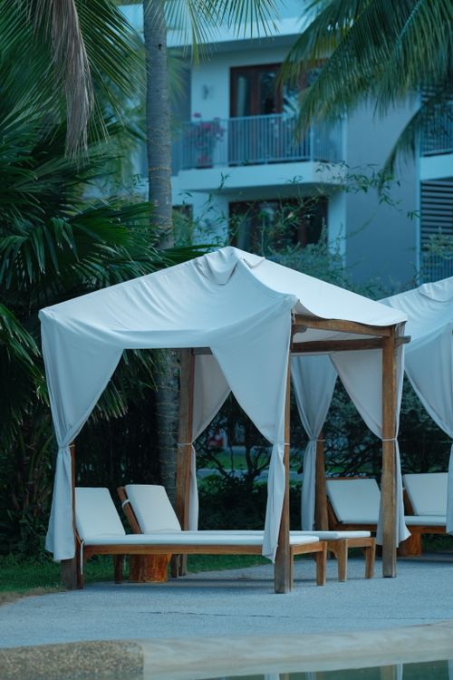 Free Quiet poolside cabana with white drapes at a tropical resort, perfect for relaxation. Stock Photo