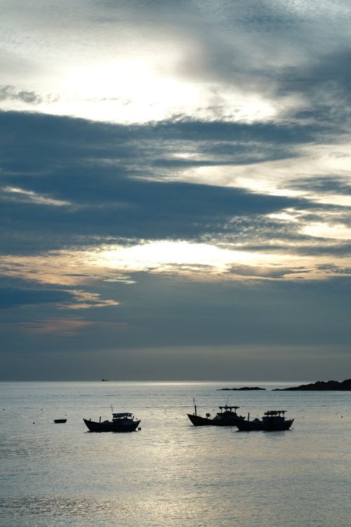 Free Peaceful sunset view with silhouetted fishing boats on calm water. Stock Photo
