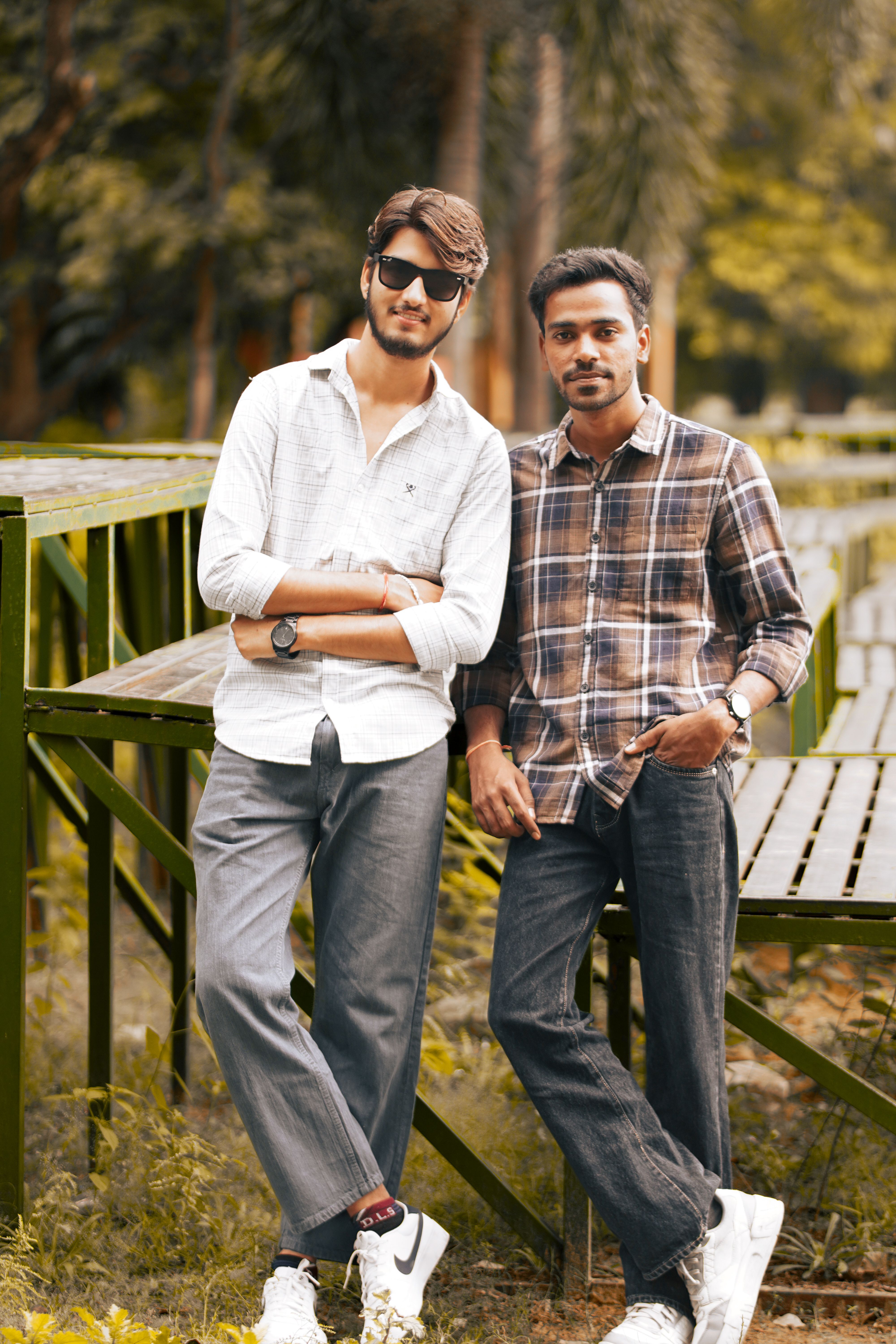 Two young men comfortably pose together outdoors, exuding a friendly vibe in casual clothing.