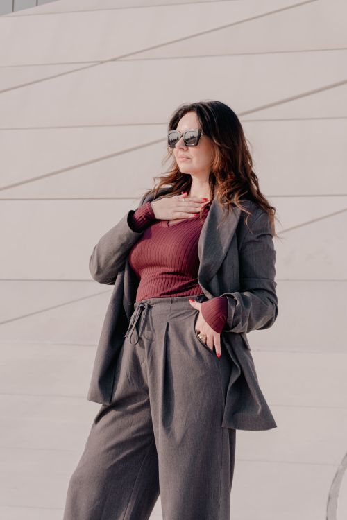 Free Stylish woman in grey suit and sunglasses posing confidently outdoors. Stock Photo