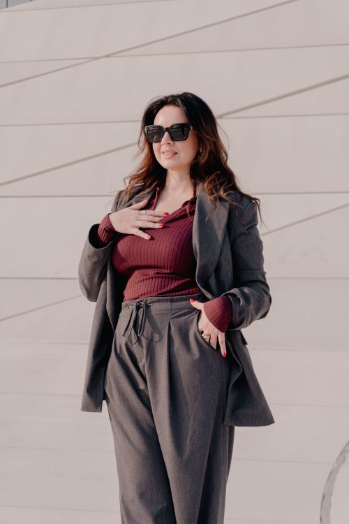 Free Confident woman in stylish suit and sunglasses standing outdoors in sunlight. Stock Photo