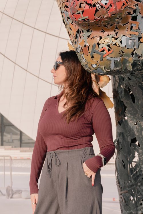 Free Fashionable woman in sunglasses poses beside a contemporary sculpture. Modern architectural backdrop. Stock Photo