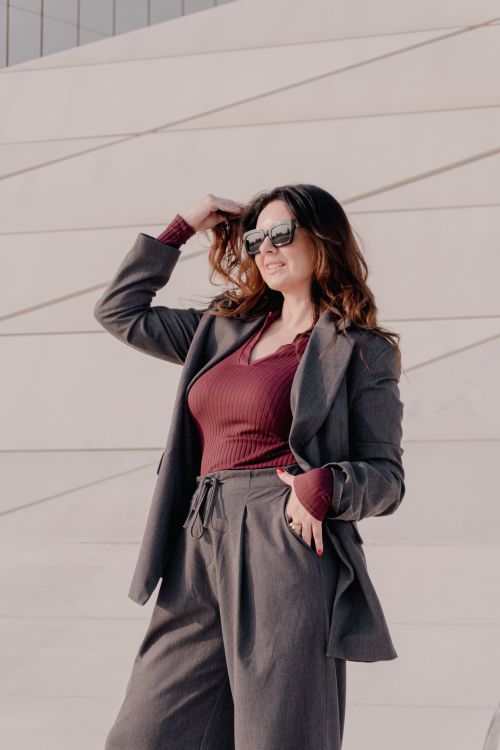 Free Confident woman in business suit and sunglasses enjoying a sunny day outside a modern architecture structure. Stock Photo