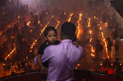 Free A father holding his child amidst a vibrant candle-lit celebration, creating a warm festive atmosphere. Stock Photo