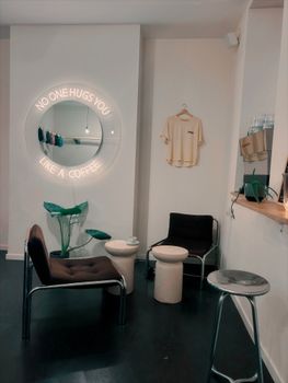 A stylish coffee shop corner in Liège featuring a neon sign and cozy seating.