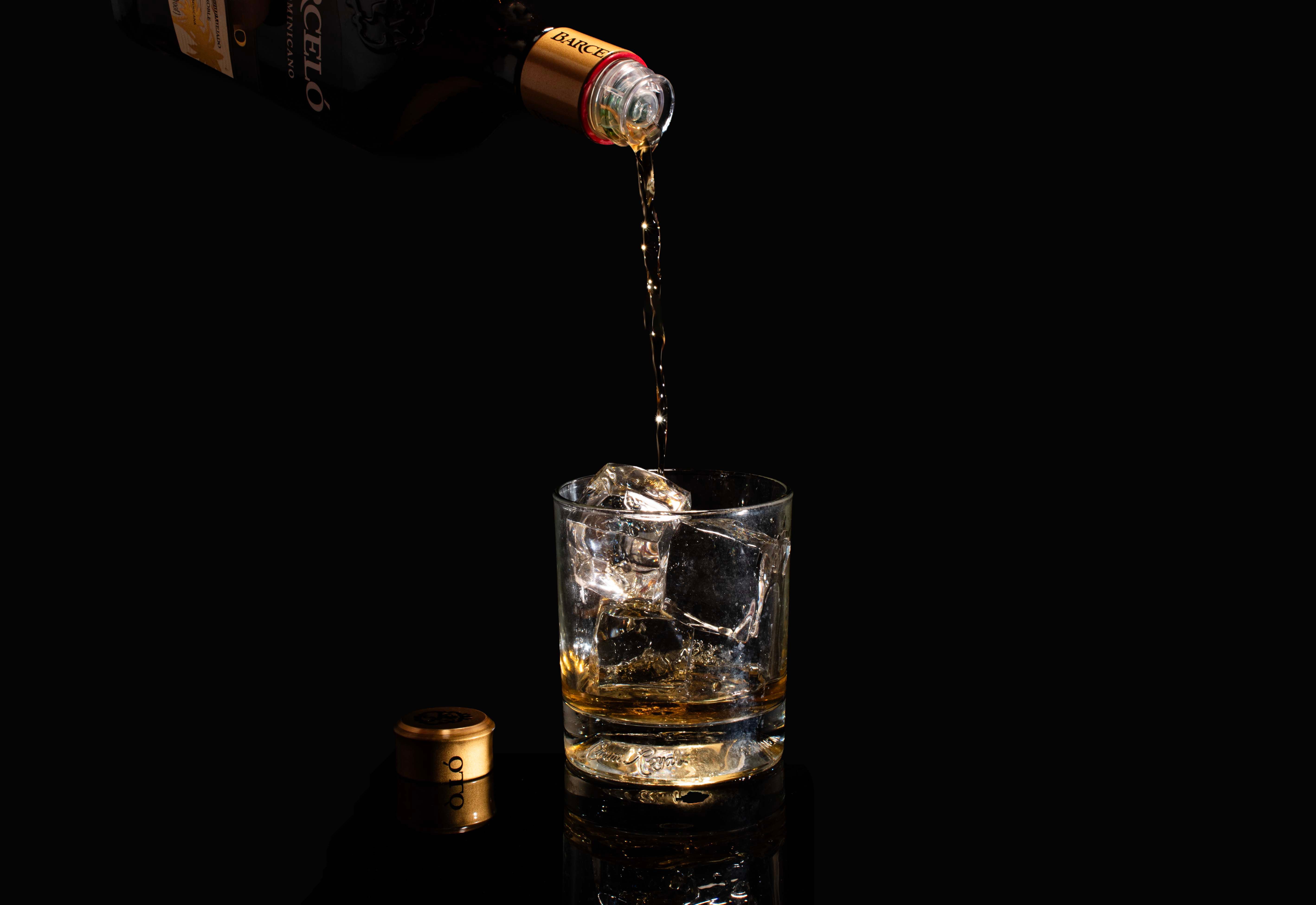 Pouring Rum into Glass with Ice Cubes · Free Stock Photo