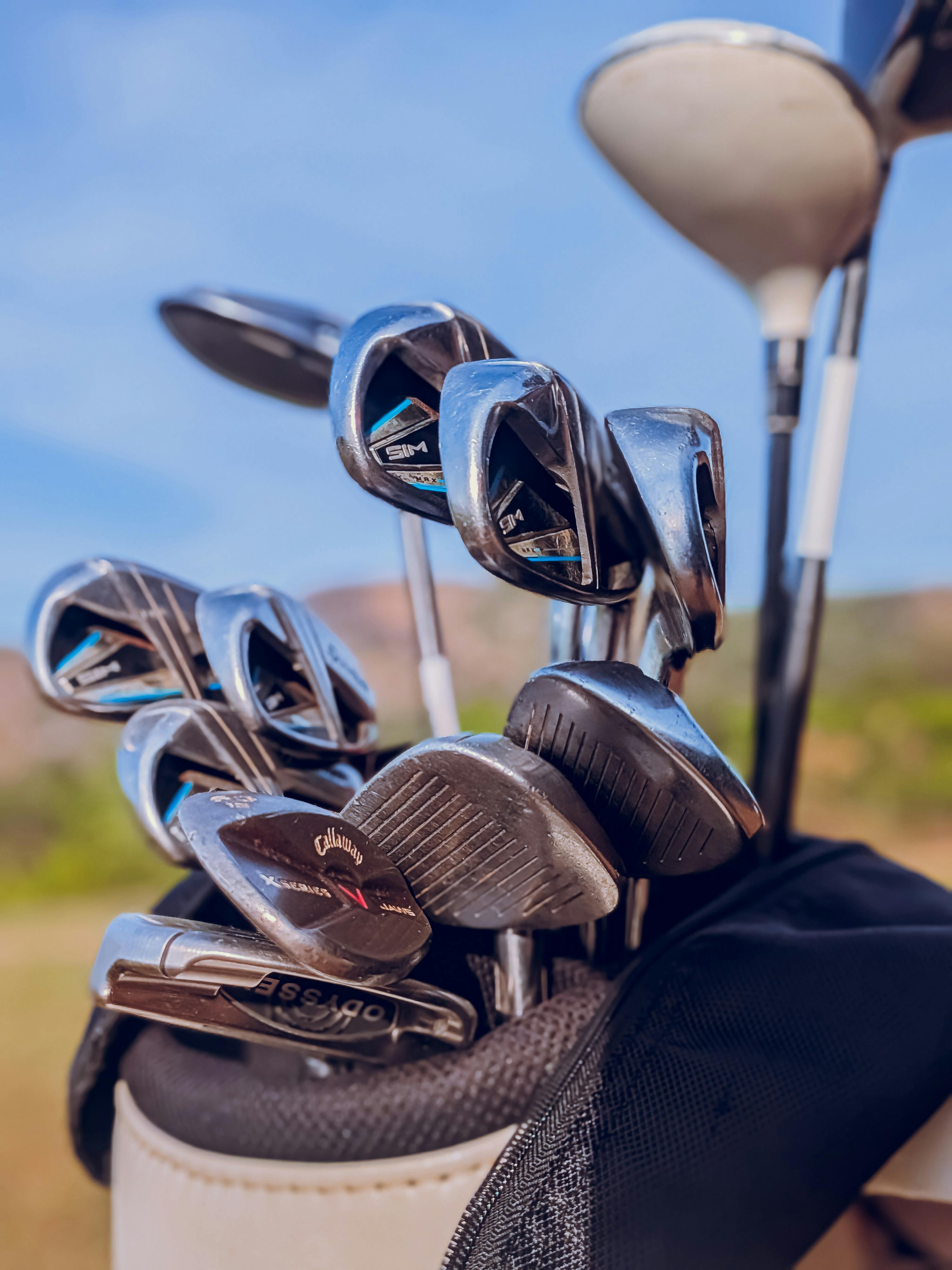 A close-up of golf clubs in a bag showing various club types on a sunny day.