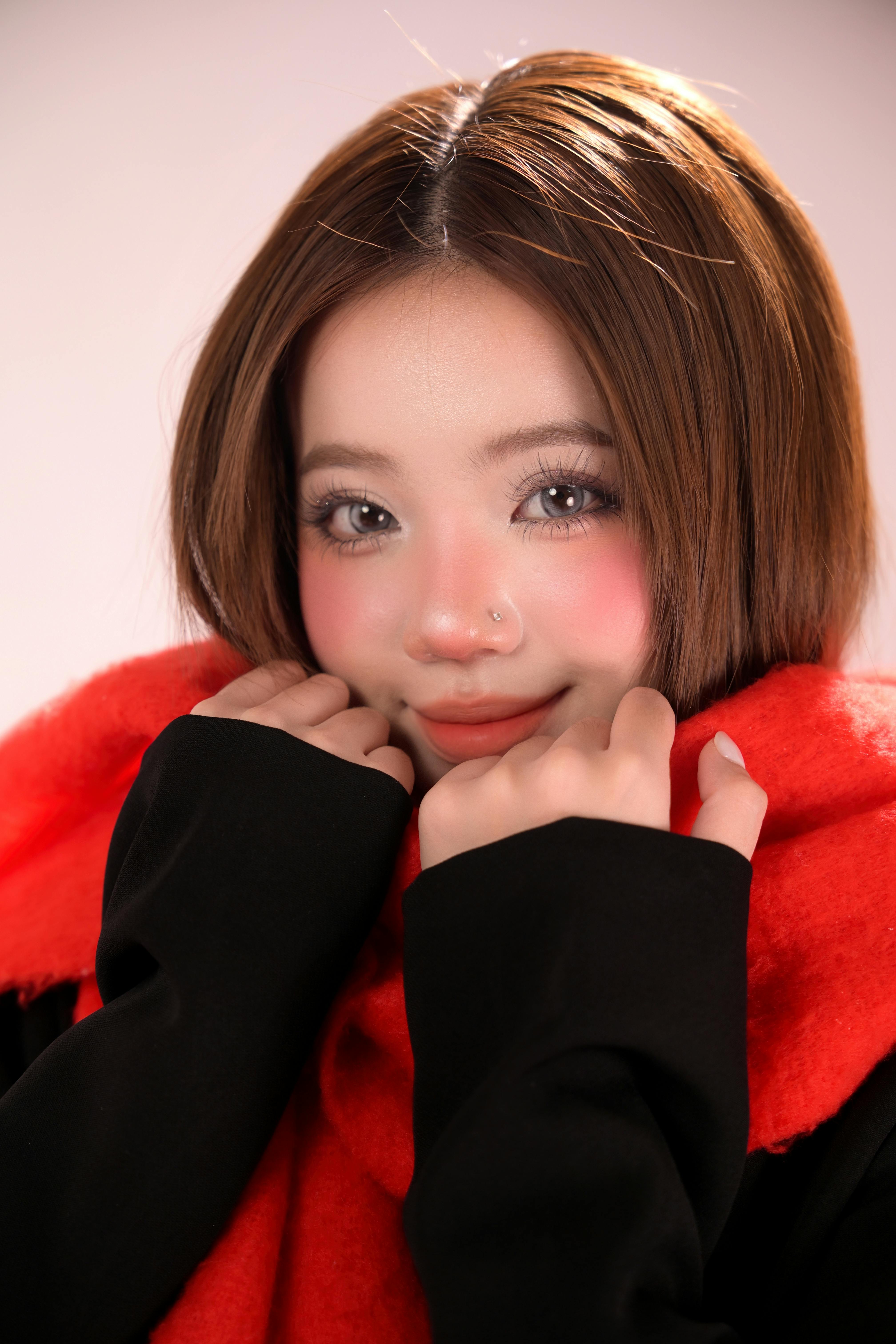 Charming portrait of a young woman wrapped in a red scarf, exuding warmth and coziness.