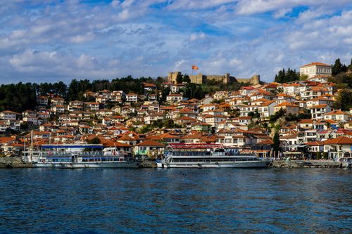 Free Beautiful panoramic view of Ohrid's red-roofed houses and Lake Ohrid, with Samuil's Fortress in the background. Stock Photo