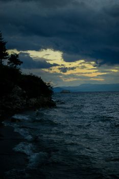A tranquil sunset over Lake Ohrid, with dramatic clouds creating a moody atmosphere.