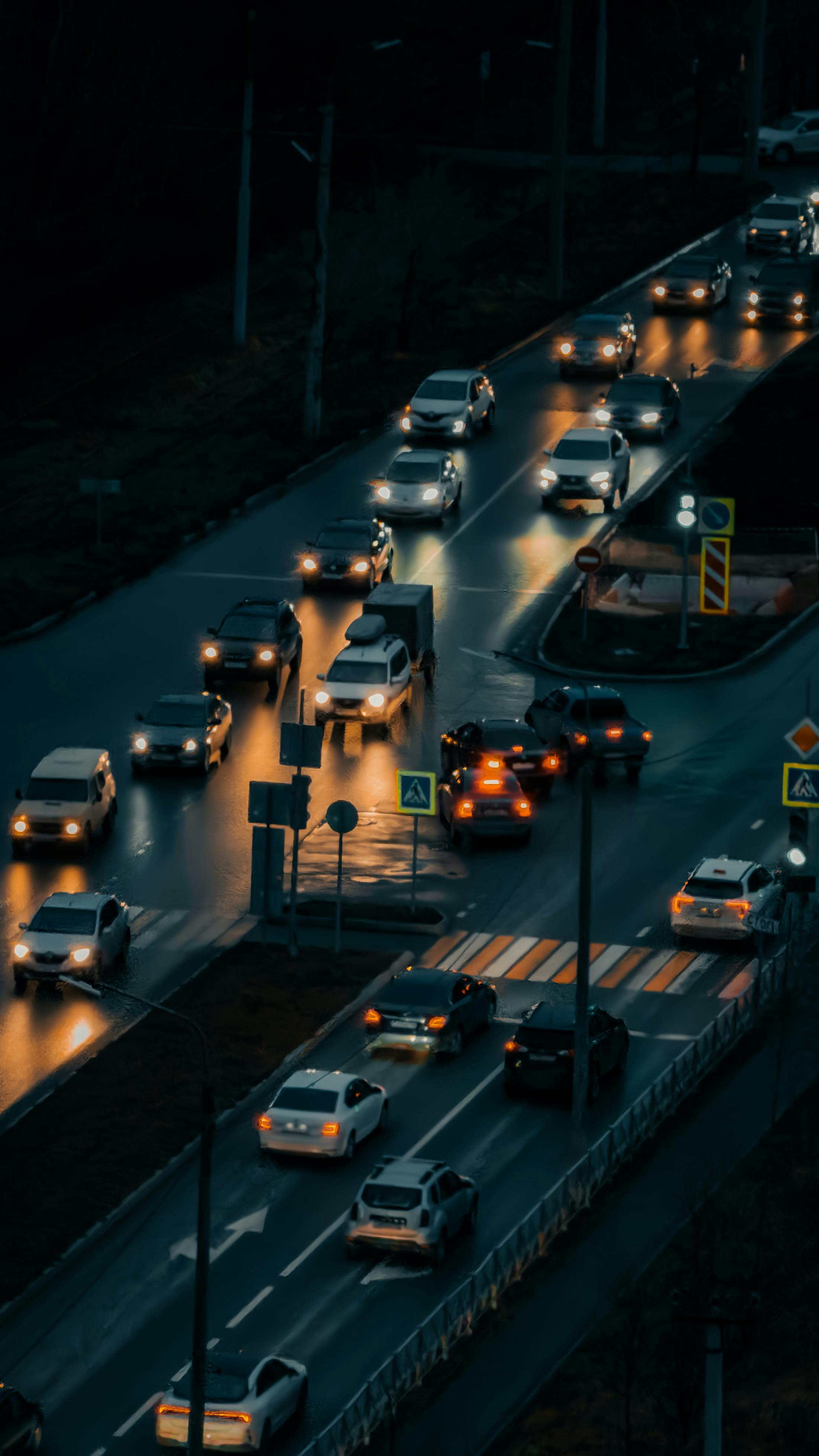Night traffic on wet city roads with cars and streetlights glowing.