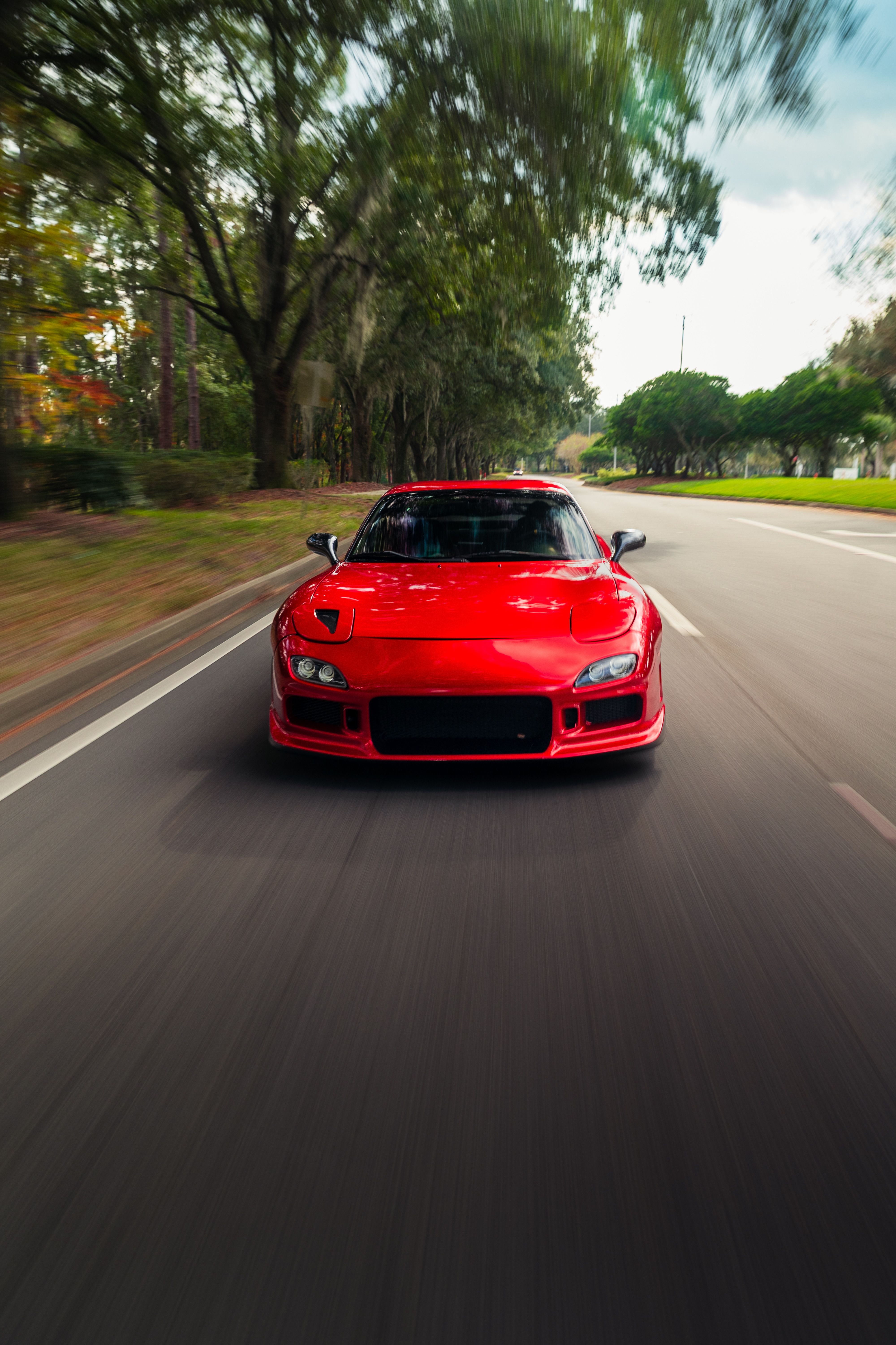 Dynamic Red Sports Car Driving on Scenic Road · Free Stock Photo