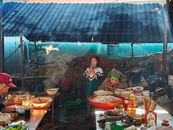 Bustling Vietnamese market scene with locals preparing and enjoying food.