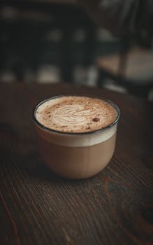 A rich cappuccino with foam art served in a rustic mug on a wooden table, perfect for coffee lovers.
