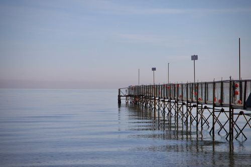 Free A peaceful wooden pier extends into calm waters under a pastel sky, offering tranquility at sunset. Stock Photo